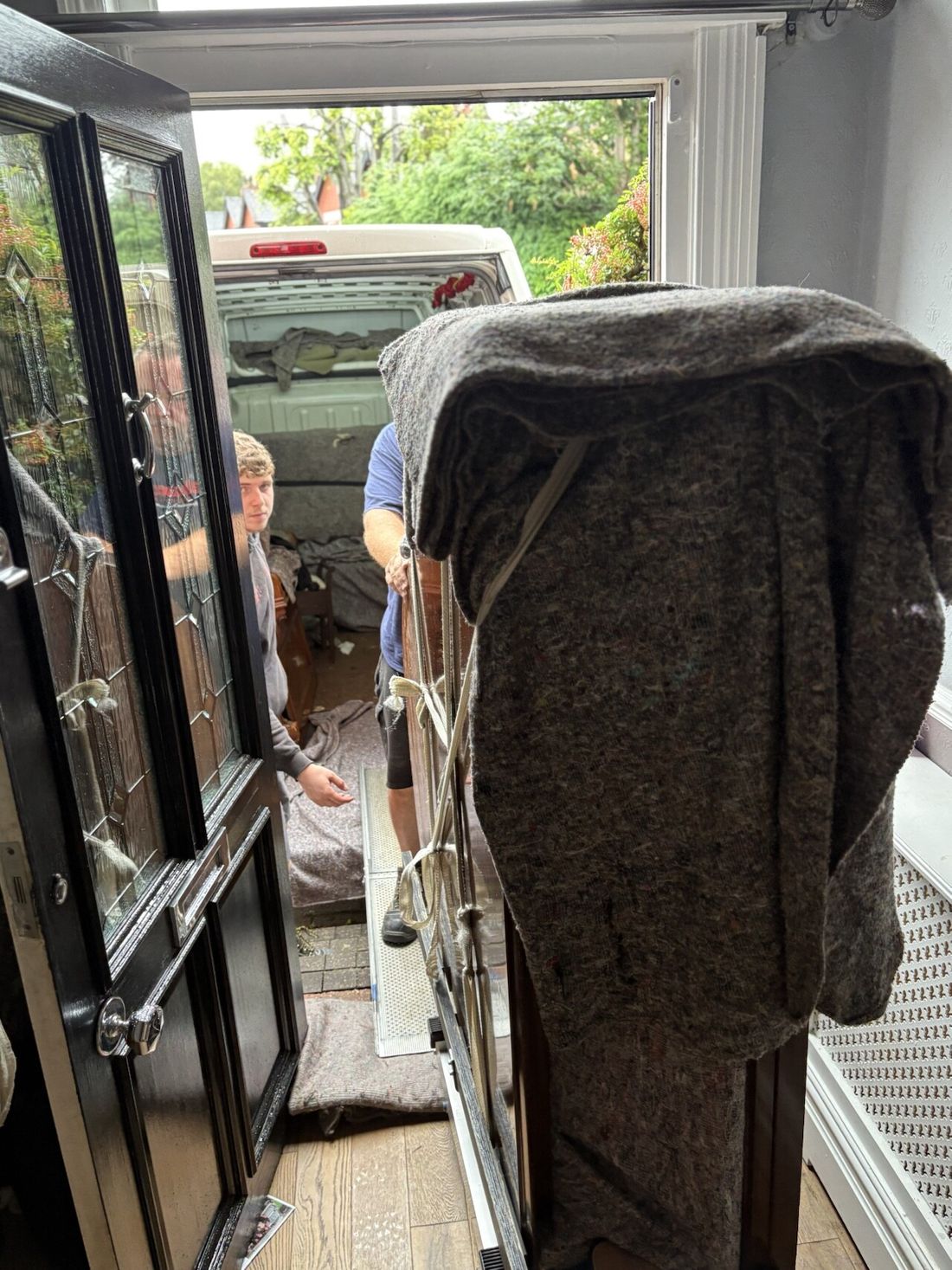 Piano Logistics Manchester movers taking an upright piano down outside steps